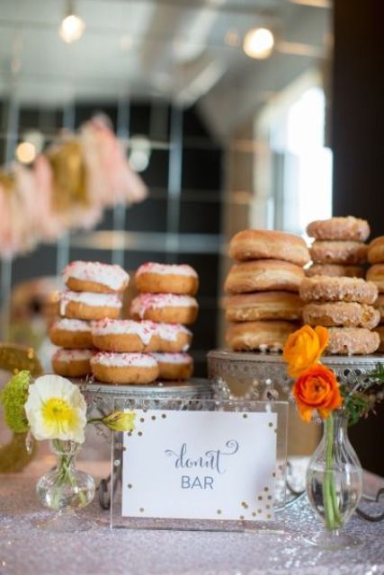 a glam donut bar with vintage-inspired donut stands, a glam pola dot sign. blooms and lots of glazed donuts
