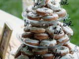 a clear glass stand with lots of glazed donuts and LOVE toppers for a casual and modern wedding