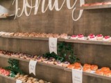 a donut wall with open shelves, greenery, signage are a very trendy and cool idea for a wedding