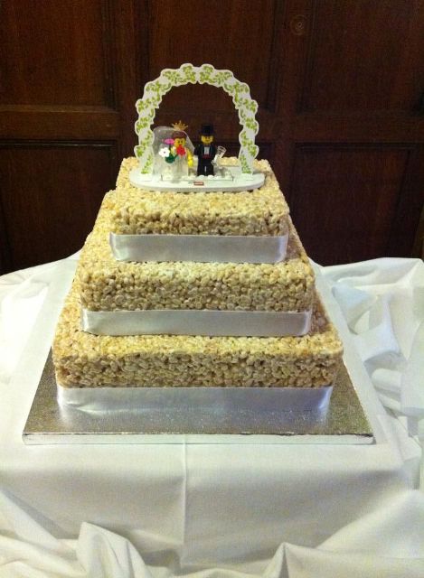 a square krispie rice wedding cake with white silk ribbons and a funny LEGO topper