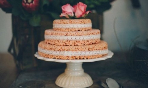 a mini krispie rice wedding cake with lace ribbons and pink roses on top is cute