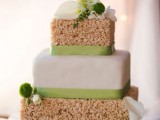a krispie rice square wedding cake with a buttercream covered tier, green ribbons, white and green blooms
