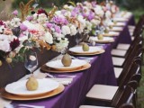 a fantastic fall wedding tablescape done with white, purple and pink blooms, a purple tablecloth and pears on each place setting as favors and for decor