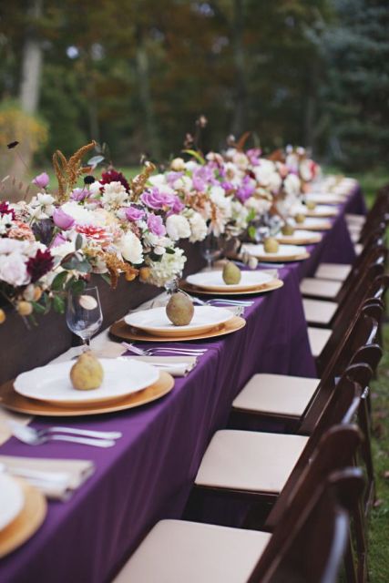 a fantastic fall wedding tablescape done with white, purple and pink blooms, a purple tablecloth and pears on each place setting as favors and for decor