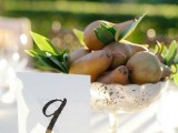 an edible wedding centerpiece of a metallic bowl with pears and foliage plus a table number is a stylish and easy idea for a fall wedding