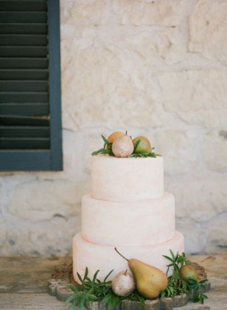 a white wedding cake topped with greenery and pears is a lovely idea for a modern fall wedding, it's simple and pretty