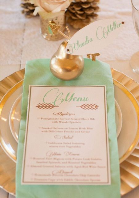 a glam wedding place setting with a gold charger, gold rim plates, a mint green napkin and a gilded pear as a place card and a favor