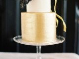 a refined modern winter wedding cake in gold and white topped with provet berries is a very chic option