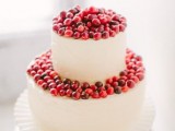 a white buttercream wedding cake topped with berries is a stylish idea for a modern winter wedding