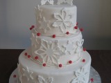 a white snowflake buttercream wedding cake with red berries is a stylish dessert for a winter celebration