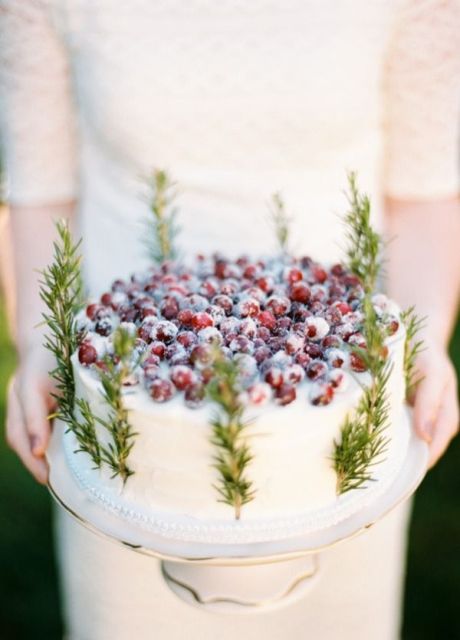 a white buttercream wedding cake with greenery and topped with sugared berries is ideal for a rustic winter wedding