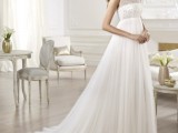 a romantic and elegant empire waist wedding dress with an embellished bodice, no sleeves and a train