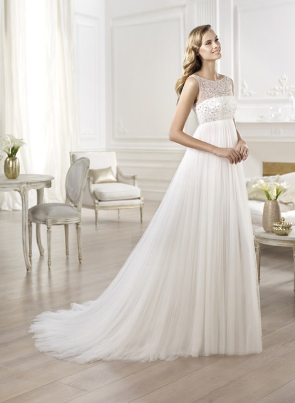 a romantic and elegant empire waist wedding dress with an embellished bodice, no sleeves and a train