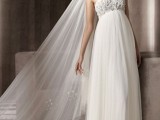 an exquisite A-line wedding dress with a lace and embellished bodice, an empire waist, a pleated skirt and a veil