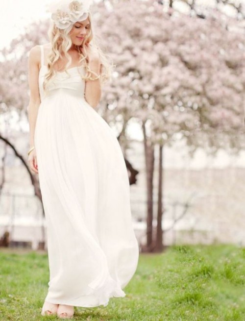 a casual white wedding dress with a draped bodice, an empire waist, a pleated skirt plus fabric blooms on the head