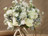 a unique winter wedding centerpiece of white blooms, pale greenery placed on gilded antlers is a very stylish and chic idea