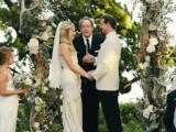 a wedding arch decorated with white blooms, olive branches and antlers is a stylish decoration to rock