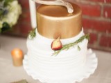 a fall wedding cake with a white and a gold tier, greenery, figs and a piece of gilded antlers on top to give a woodland feel to the dessert