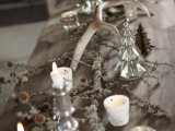 a winter wedding table decorated with candles in mercury glass candleholders, pinecones and antlers is a beautiful decadent-like idea
