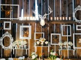 a bold rustic gallery wall of empty frames, blooms and faux taxidermy is a creative idea to decorate your wedding venue