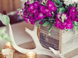 a rustic centerpiece of a burlap runner, antlers, candles and a reclaimed wood box with super bright flowers is very cool and bold