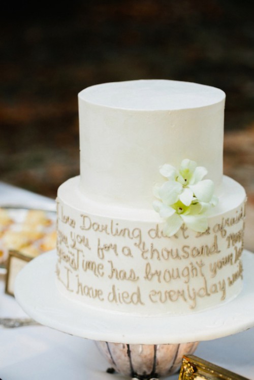 a plain white wedding cake decorated with gold calligraphy and white blooms is a chic and cool idea for any modern wedding