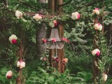 a bold wedding arch of branches and twigs, with moss, white and hot pink blooms and a crystal chandelier with pink flowers