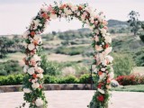 a bright and cool wedding arch with red and white blooms and greenery is a stylish and chic idea