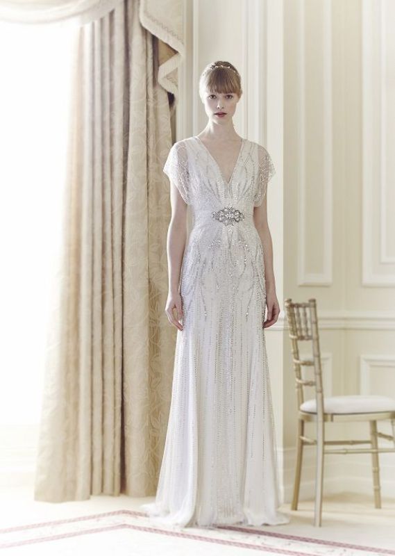A white 1920s inspired wedding dress with silver embellishments, cap sleeves and an embellished sash