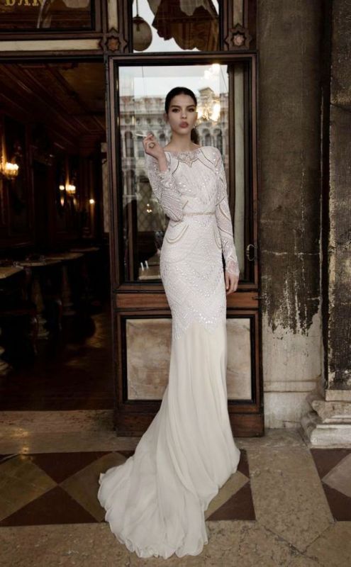 a fitting fully embellished wedding dress with long sleeves, a high neckline, a train and an embellished sash