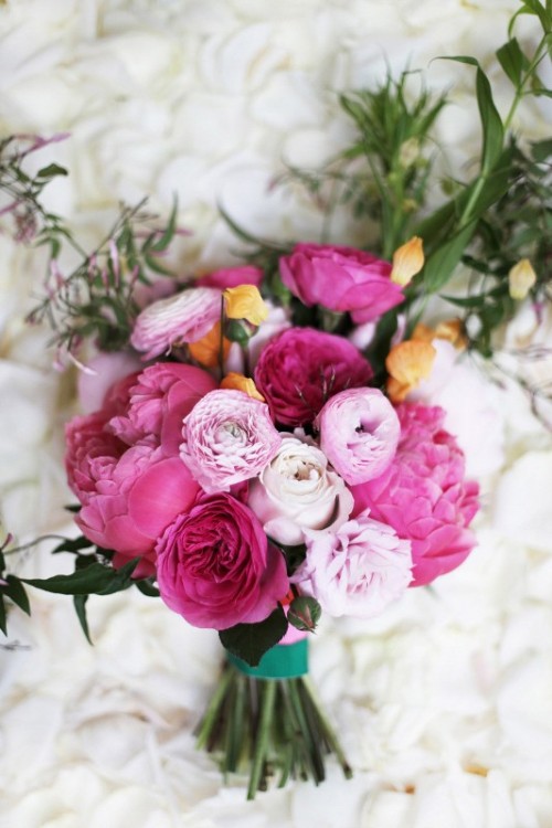 a pink and light pink wedding bouquet with peonies, ranunculus, yellow garden roses for a spring or summer wedding