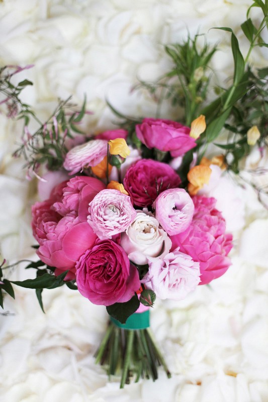 A pink and light pink wedding bouquet with peonies, ranunculus, yellow garden roses for a spring or summer wedding