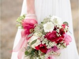 a light and deep pink wedding bouquet with some smaller white fillers and greenery, pink ribbon is a chic idea for a spring or summer wedding