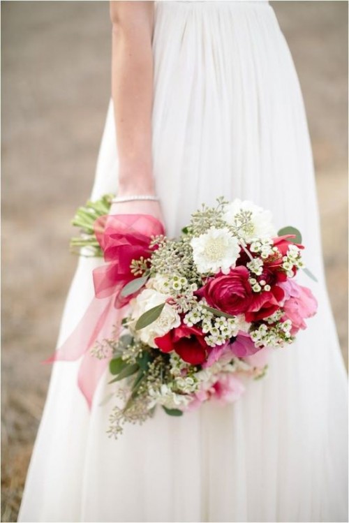 a light and deep pink wedding bouquet with some smaller white fillers and greenery, pink ribbon is a chic idea for a spring or summer wedding