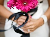 a laconic and dramatic pink gerbera wedding bouquet with black ribbon is a catchy idea for a pink and black wedding