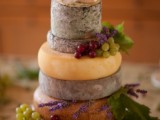 a cheese wheel wedding cake decorated with fresh grapes and greenery will be a nice pair for a glass of wine