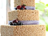 a krispy rice wedding cake topped with fresh berries and fruits and decorated with lilac ribbons