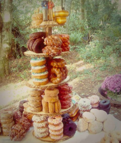 a creative wooden stand with an assortment of glazed donuts for a rustic or woodland wedding