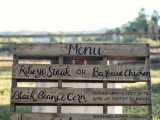 a rustic wedding menu written on a large pallet is a cute idea for a rustic or a backyard wedding