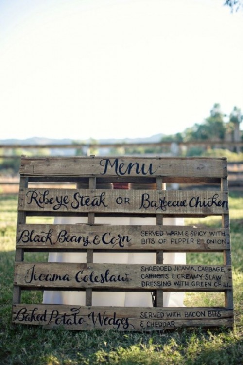 a rustic wedding menu written on a large pallet is a cute idea for a rustic or a backyard wedding
