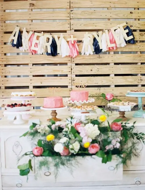 a pallet backdrop with colroful letters and tassel garlands can be used anywhere throughout your wedding venue