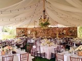 a large long pallet backdrop with blooms, candles and monograms for the wedding reception with a rustic feel