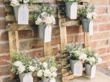 pallet vertical gardens with buckets, fresh blooms and greenery plus tags for a rustic wedding