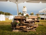 a dessert table fully made of pallets with candles, floral arrangements and a wedding cake on top