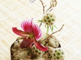 an arrangement of moss, blooms and twigs with wedding rings on top is great for an exotic wedding