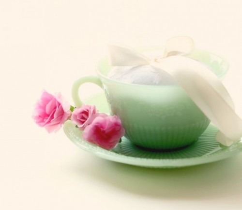 a green teacup with a saucer filled with white fabric is a whimsy and fun idea for an Alice in Wonderland wedding