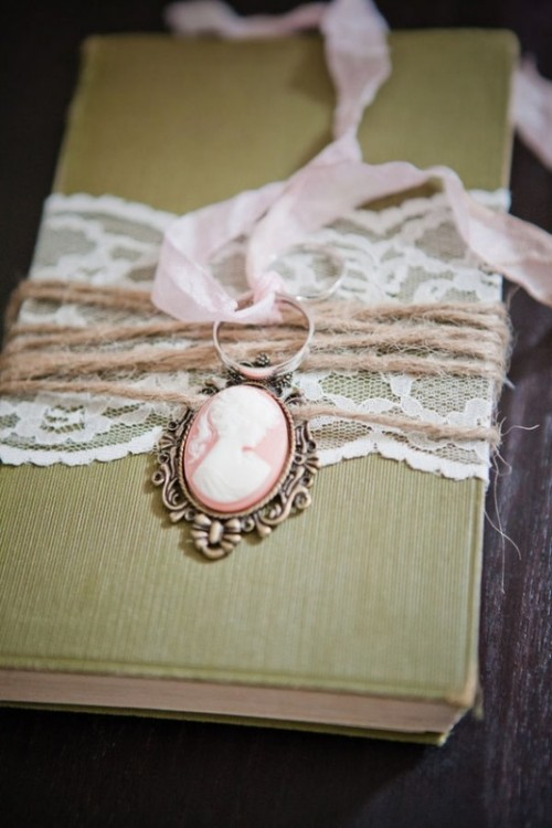 a green book with lace and twine plus a vintage necklace on top is a cool idea to attach your rings