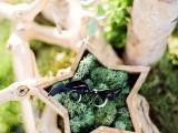 a wooden star filled with moss and with rings is a creative idea for a woodland wedding