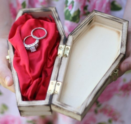 a coffin with red fabric is a creative alternative to a ring pillow for a Halloween wedding