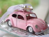 a pink retro car with a veil and rings on top is a whimsy idea for a retro wedding
